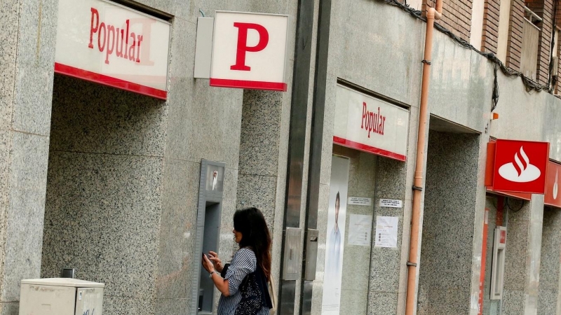 Una foto de junio de 2017 de una mujer utilizando el cajero automático de una oficina del extinto Banco Popular, junto a otra sucursal del Banco Santander. REUTERS/Albert Gea