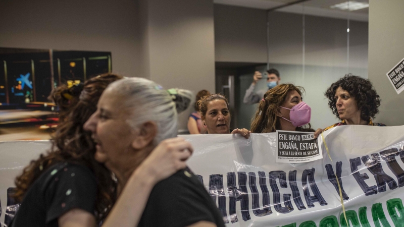 Miembros de la PAH Vallecas durante una protesta en una oficina de CaixaBank para exigir una negociación con el banco para evitar 13 desahucios.