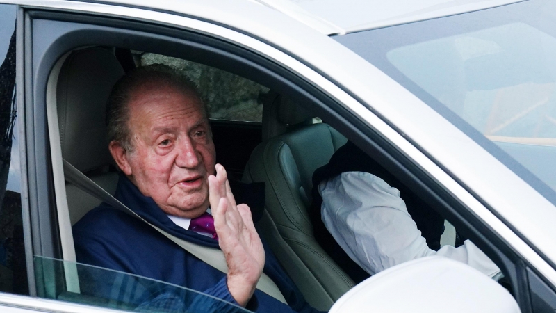 El rey emérito Juan Carlos I saluda desde un vehículo a su salida de la casa de Sanxenxo camino de Madrid, a 23 de mayo de 2022, en Sanxenxo.