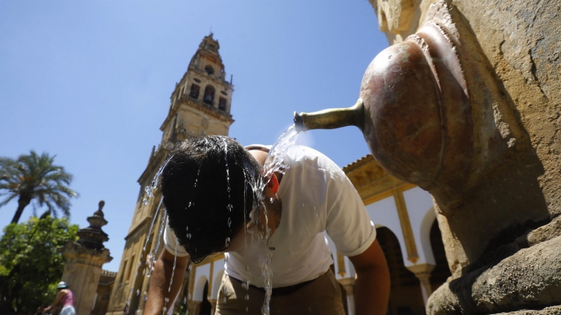 un turista se refresca en una de las fuentes del Patio de los Naranjos de la Mezquita catedral de Córdoba para aliviar las altas temperaturas.