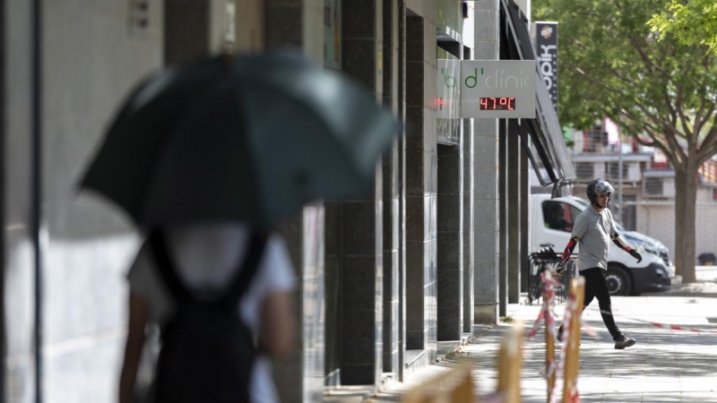 15/06/2022 Una joven camina por una calle bajo un termómetro que indica los 47ºC este miércoles, tercer día de ola de calor en Cataluña, que, según las previsiones, aún será más sofocante mañana, para alcanzar su máximo el viernes, a 15 de junio de 2022,