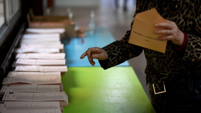 Una mujer recoge una papeleta en un colegio electoral en Madrid durante las elecciones regionales de Madrid el 4 de mayo de 2021.- AFP