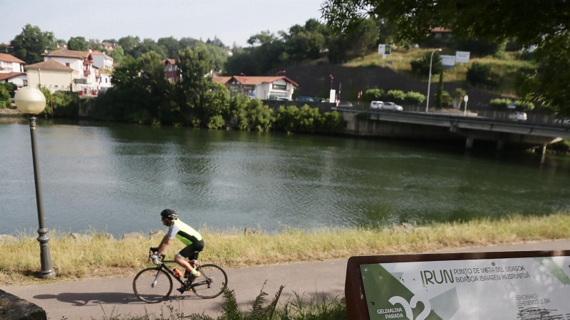 Un ciclista pasa por las inmediaciones del río Bidasoa a su paso por Irún este sábado.
