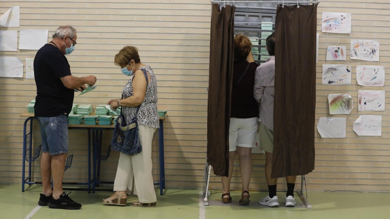 Varias personas cogen papeletas para ejercer su derecho al voto en el CEIP Malala de Mairena del Aljarafe en Sevilla