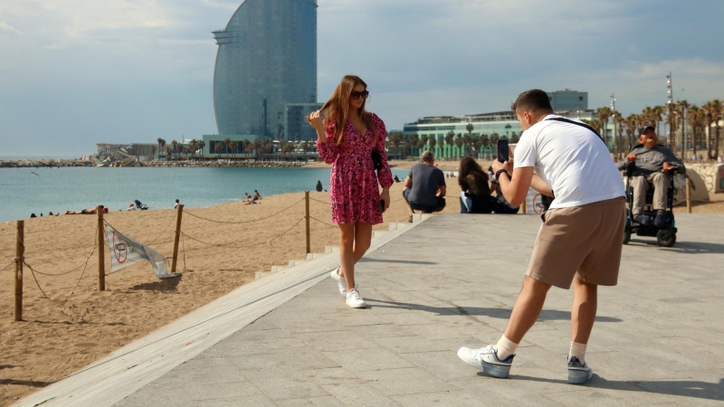 08/05/2022 - Dos turistes fent-se una foto a la Barcelona, amb l'hotel W de fons.