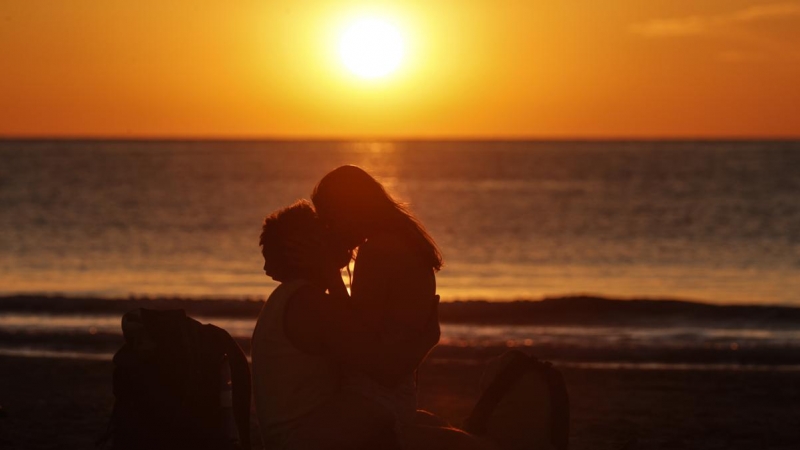 Una pareja se besa frente al mar mientras amanece, este viernes 24 de junio de 2022, en la playa de La Malvarrosa de València, tras la Noche de San Juan.