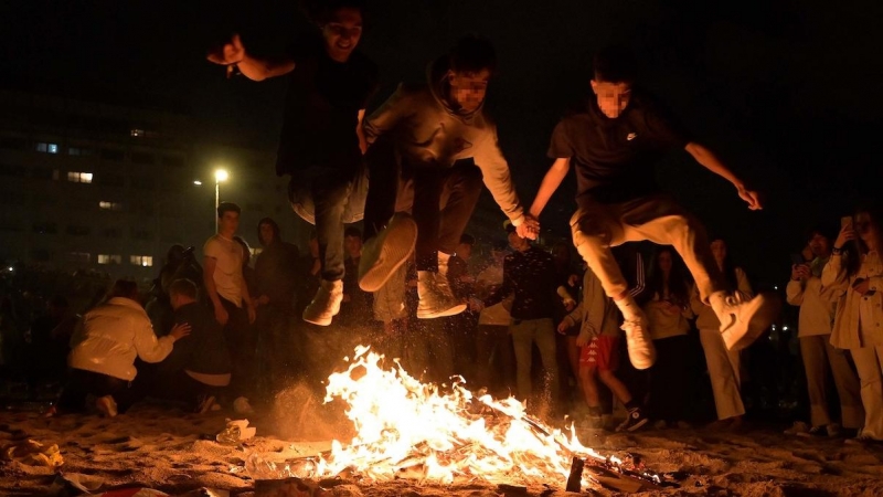 Varios jóvenes saltan una hoguera en la Noche de San Juan, a 23 de junio de 2022, en A Coruña, Galicia.