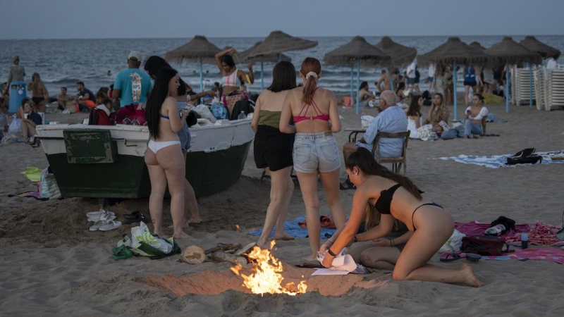 Varias personas preparan una hoguera sobre madera en la playa de la Malvarrosa durante la Noche de San Juan, a 23 de junio de 2022, en Valencia.