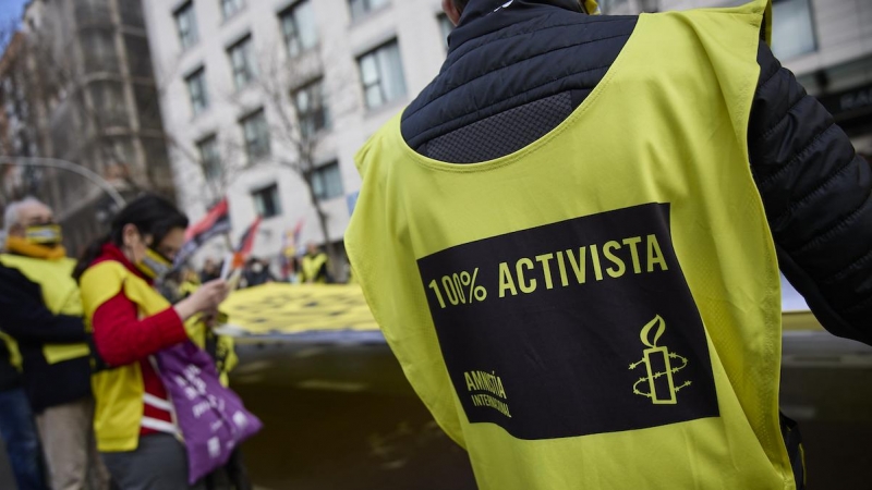 Varias personas portan una banderola amarilla gigante de Amnistía Internacional que reza 'Que ni los besos te callen' en una manifestación contra la ley mordaza, a 13 de febrero de 2022, en Madrid.