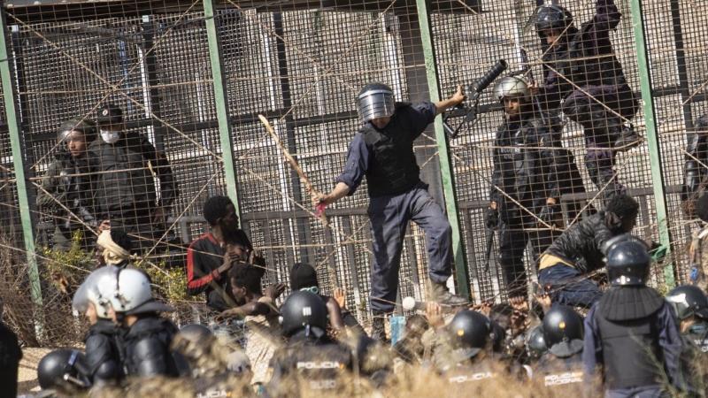 Un agente marroquí golpea desde territorio español con un palo a los migrantes que lograron saltar la valla de Melilla el pasado viernes.