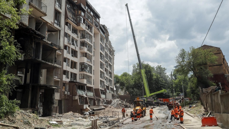 Los trabajadores comunales limpian los escombros frente a un edificio residencial dañado luego de los ataques aéreos rusos en el distrito Shevchenkivskiy de Kyiv (Kiev), Ucrania, el 26 de junio de 2022.