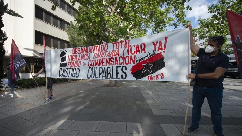 28/06/2022. Dos hombres sujetan una pancarta durante una concentración por los trabajadores fallecidos por el amianto frente a los Juzgados de Plaza de Castilla, a 14 de junio de 2021, en Madrid.