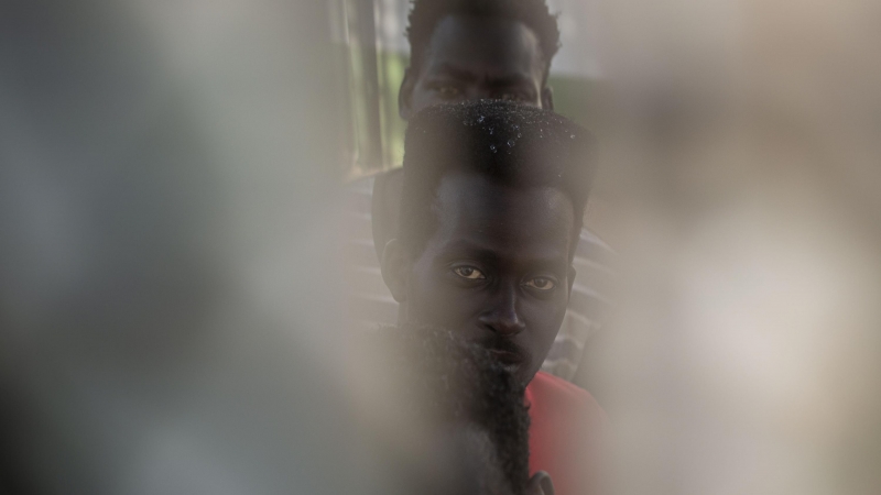 Tres de los migrantes que lograron cruzar a Melilla el pasado viernes, visto por una rendija en el Centro de Estancia Temporal para Migrantes (CETI), donde están en en cuarentena.