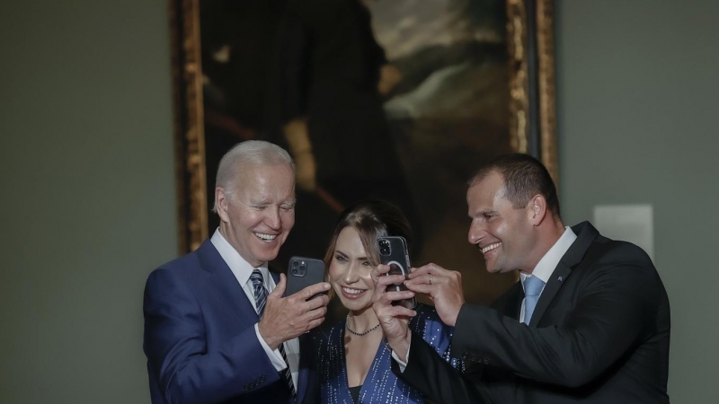 El presidente de los Estados Unidos, Joe Biden (i), enseña su teléfono a la primera ministro de Nueva Zelanda, Jacinda Arderna (c), a su llegada a la cena que el jefe del Ejecutivo ofrece a los jefes de Estado y jefes de Gobierno que participan en la cumb