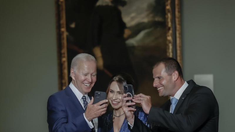 El presidente de los Estados Unidos, Joe Biden (i), enseña su teléfono a la primera ministro de Nueva Zelanda, Jacinda Arderna (c), a su llegada a la cena que el jefe del ejecutivo español ofrece a los jefes de Estado y jefes de Gobierno que participan en