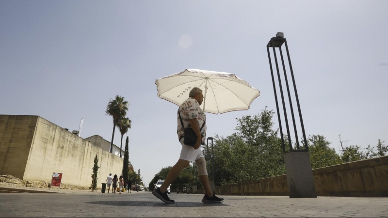 Un hombre se protege del sol con una sombrilla en una jornada de intenso calor.