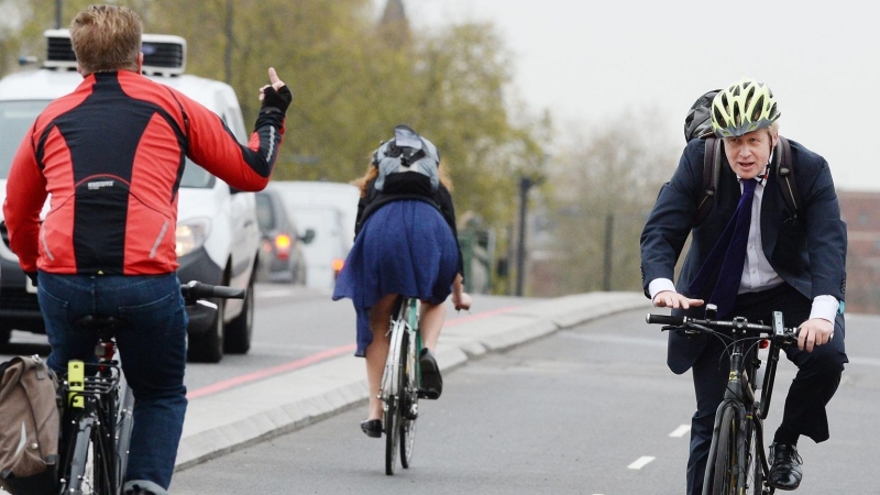 Boris Johnson recibe el saludo de un ciudadano mientras pasea en bicicleta.