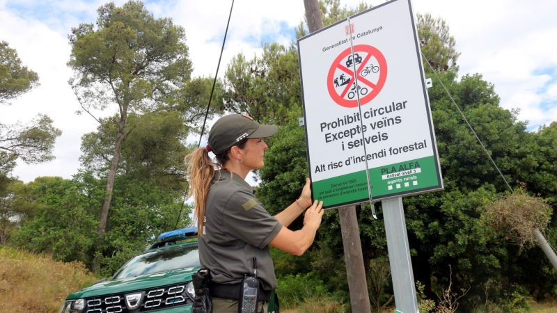 07/07/2022 - Una agent rural col·loca un cartell que informa del tancament del Parc Natural del Montgrí.