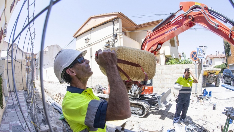 Un operario bebe agua en un descanso mientras realiza tareas de canalización de aguas en una calle de Granada