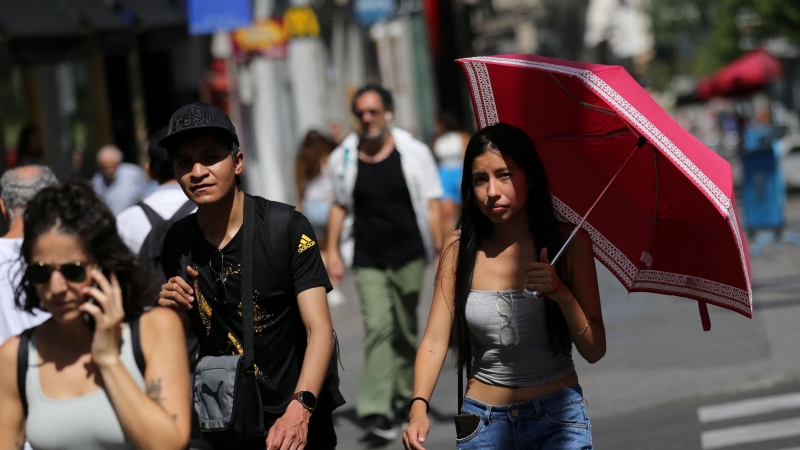 Una mujer se protege del sol bajo un paraguas mientras camina por la Gran Vía durante la segunda ola de calor del año en Madrid, España, el 15 de julio de 2022.