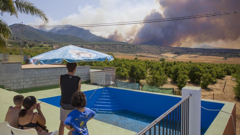 Varios vecinos contemplan el incendio declarado este mediodía en el paraje El Higuerón de Mijas (Málaga)