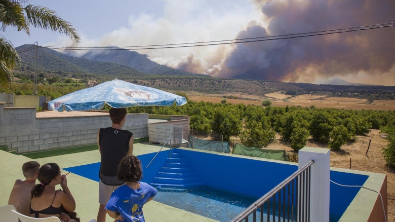 Varios vecinos contemplan el incendio declarado este mediodía en el paraje El Higuerón de Mijas (Málaga)