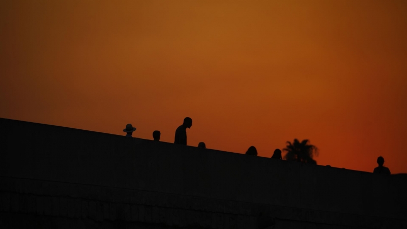 Varias personas pasean por el puente romano de Córdoba al atardecer en una jornada donde continua la ola de calor con temperaturas que alcanzan los 43 grados.