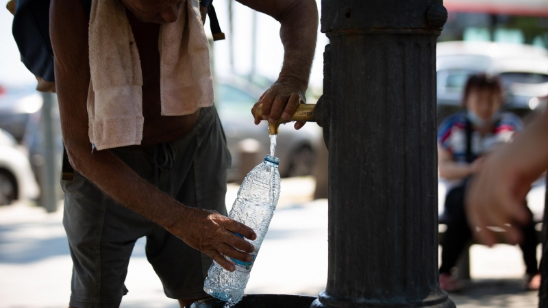 Un hombre rellena una botella de agua en una fuente en el parque de la Barceloneta, a 13 de julio de 2022, en Barcelona, Catalunya (España).