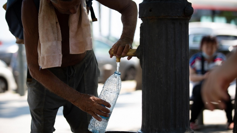 Un hombre rellena una botella de agua en una fuente en el parque de la Barceloneta, a 13 de julio de 2022, en Barcelona, Catalunya (España).