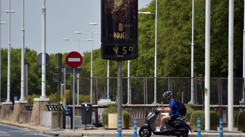 18/07/2022 - Una persona pasa en bicicleta por delante de un termómetro que marca 45º durante la ola de calor en Sevilla, el 10 de julio de 2021.