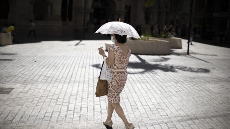 Una mujer se protege del intenso calor en una calle del centro histórico de Valencia. La Conselleria de Sanidad ha declarado el nivel de alerta sanitaria por ola de calor alto en municipios de seis comarcas de la Comunitat Valenciana.