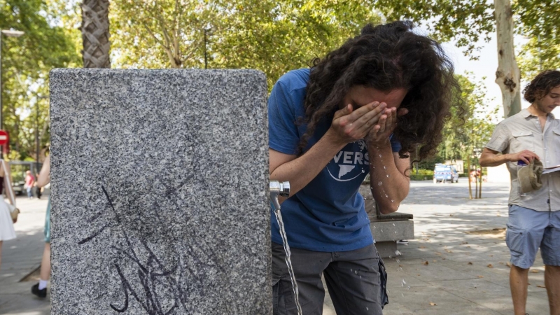 Un hombre se refresca en un grifo de agua público en medio de temperaturas abrasadoras por la actual ola de calor en España