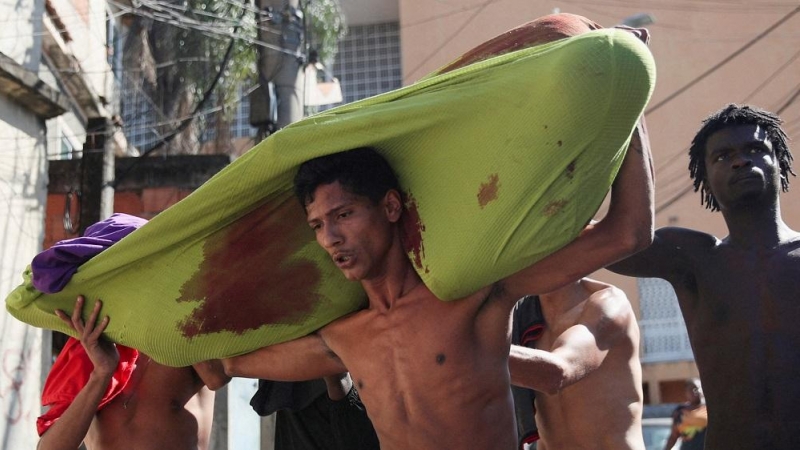 Personas cargan un cadáver durante una operación policial contra bandas de narcotraficantes en el complejo de favelas de Alemao, en Río de Janeiro