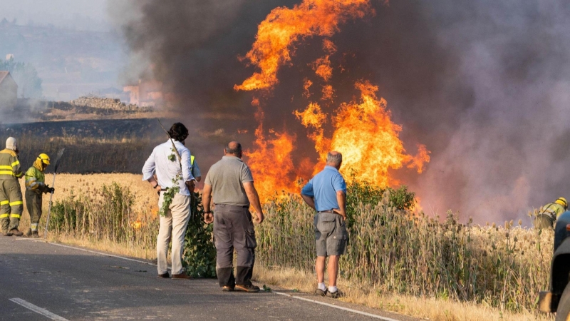 Varios vecinos observan las llamas del incendio declarado este domingo por la tarde en el término municipal de Quintanilla del Coco, en Burgos.