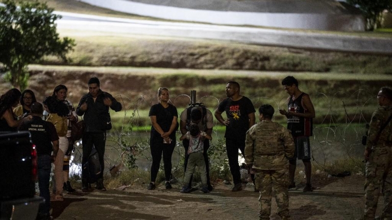 Los migrantes son detenidos por tropas de la Patrulla Fronteriza y la Guardia Nacional de EE. UU. en Eagle Pass, Texas, cerca de la frontera con México, el 30 de junio de 2022.