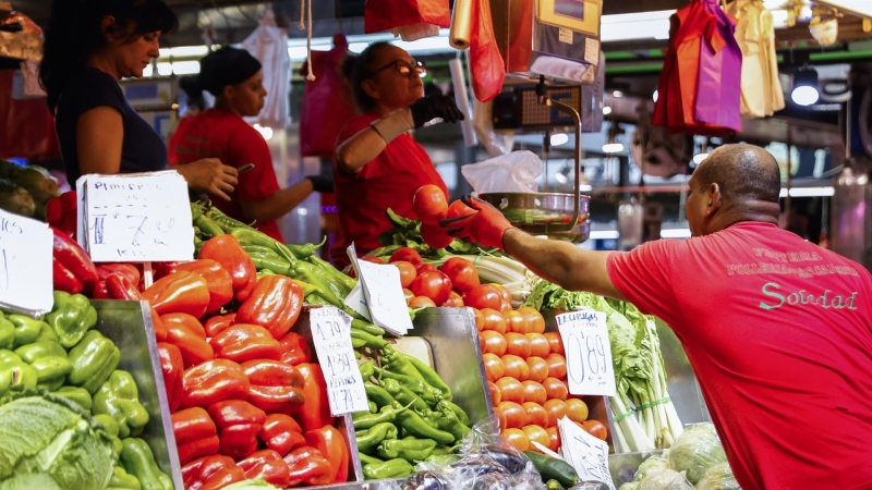 Un hombre compra en un puesto de fruta y verduras de un mercado de Madrid.