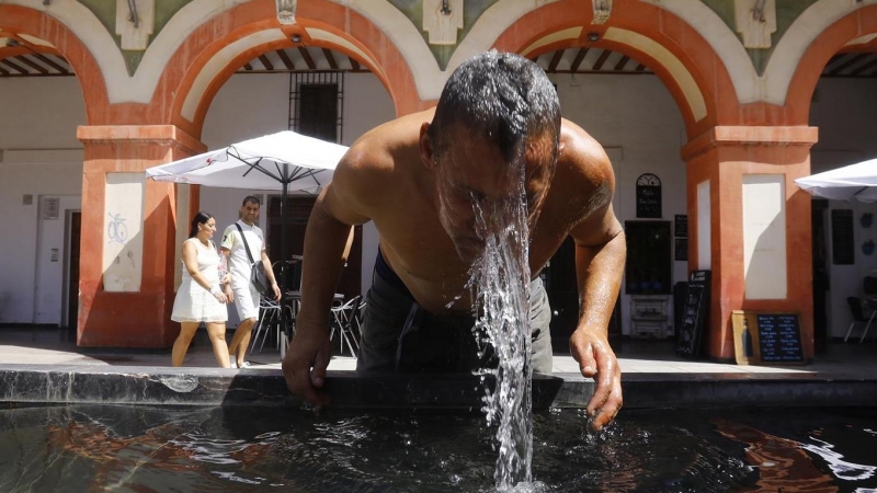 Un hombre se refresca en la fuente de la plaza de la Corredera de Córdoba