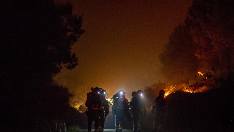 Varios bomberos forestales trabajan en la extinción del incendio de Cures, en Boiro, A Coruña, en la madrugada de este sábado.