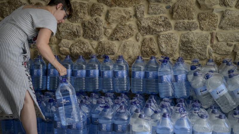 08/08/2022 Una mujer coge una botella de agua embotellada en el local que el Gobierno local de Ribadavia ha habilitado para que se abastezcan los vecinos más afectados por los cortes de suministro, a 7 de agosto de 2022
