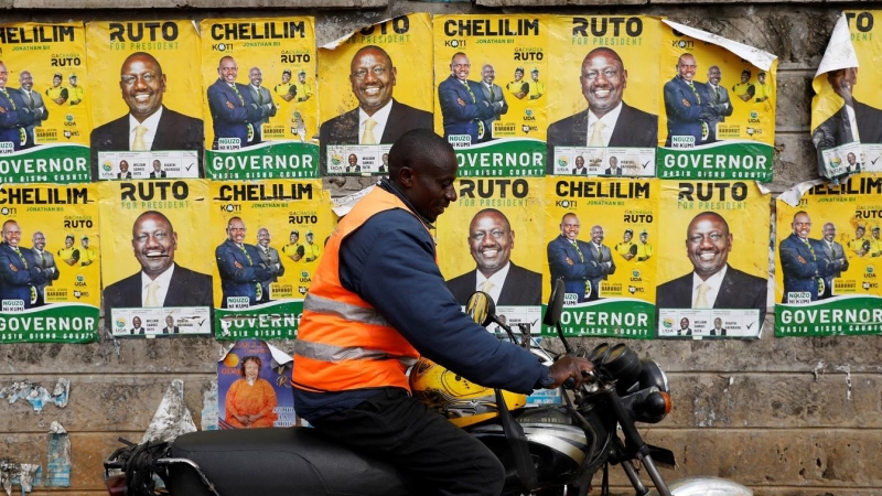 Un motorista pasa junta a una pared empapelada con los carteles electorales del actual vicepresidente de Kenia, y aspirante a la presencia, William Ruto, en las elecciones generales, en la localidad keniata de Eldoret. REUTERS/Baz Ratner