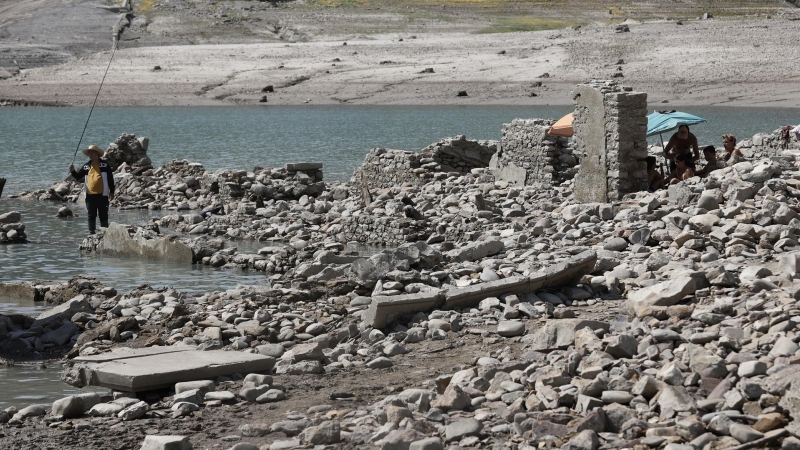 Un grupo de personas se protege del sol con una sombrilla en el pantano de Yesa donde se aprecia ya la bajada de la cota de agua dejando al descubierto las ruinas del pueblo. Toda Navarra se encuentra en situación de sequía desde el mes de julio, cuando l