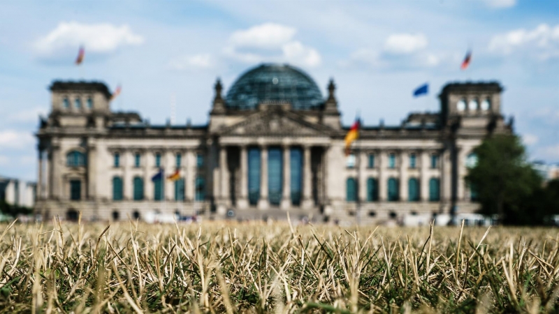 La hierba frente al edificio del Reichstag, la sede del Bundestag del Parlamento alemán, se seca durante las altas temperaturas, en el parque Lustgarten en Berlín, Alemania, el 04 de agosto de 2022. El Servicio Meteorológico Alemán (DWD) espera que la ola