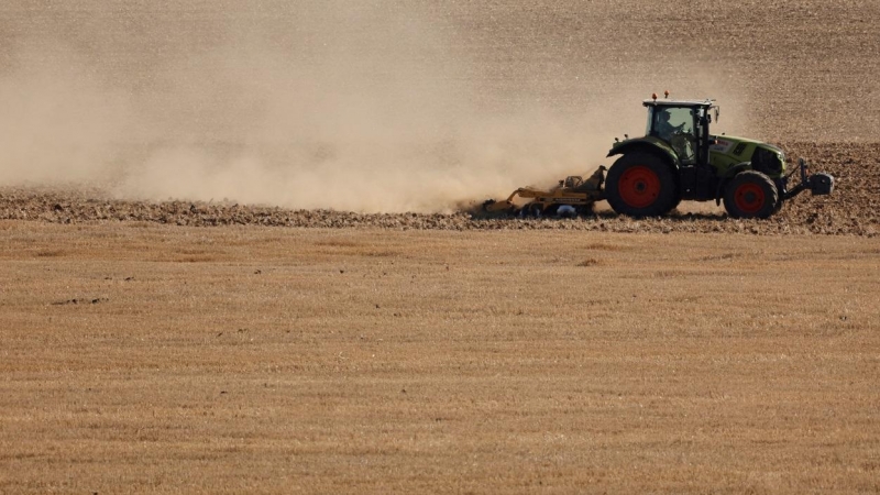11/08/2022 Un agricultor conduce un tractor en medio de una nube de polvo mientras trabaja en un campo durante una sequía en Rancourt.