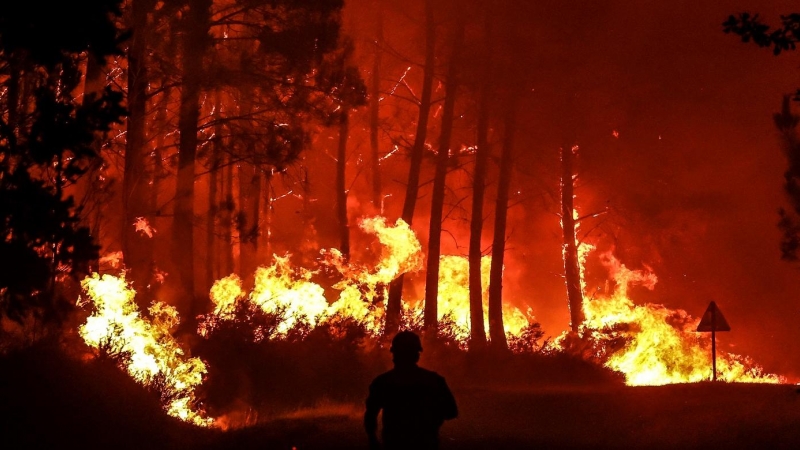 11/08/2022-Una silueta se ve delante de las llamas en un incendio forestal cerca de Belin-Beliet, suroeste de Francia, durante la noche del 11 de agosto de 2022. Las autoridades francesas han advertido de que las llamas podrían provocar un gran incendio f