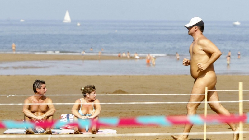 (9/09/06) Una pareja toma el sol mientras un hombre participa en la carrera nudista 'Patxi Ros' de Sopelana (Euskadi), a 9 de septiembre de 2006.