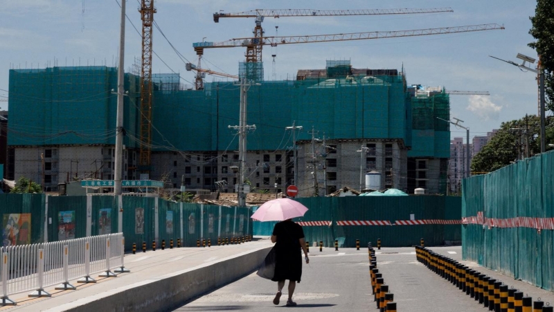 Una mujer pasa junto a varios edificios de apartamentos en construcción en Pekín. REUTERS/Thomas Peter