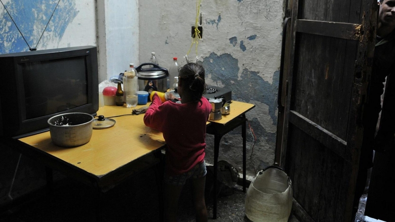 Fotografía de archivo fechada el 10 de septiembre de 2008 que muestra a una niña mientras lava platos en una improvisada cocina en el poblado José Martí, municipio de San Cristóbal, provincia de Pinar del Río