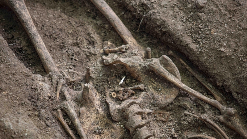 Un botón y una hebilla hallados junto a los huesos de exhumados en el cementerio de Colmenar Viejo.