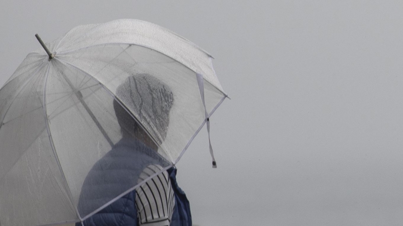 Una hombre camina bajo la lluvia en San Sebastián.