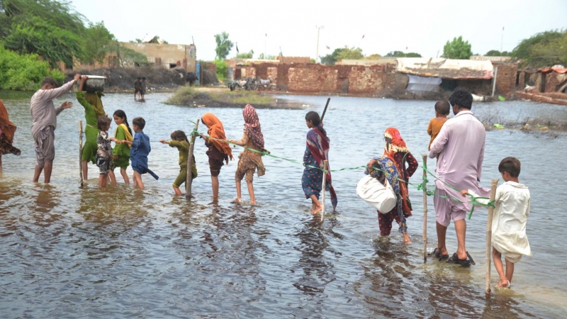 Varias familias tratan de atravesar una zona inundada en la provincia de Sindh.